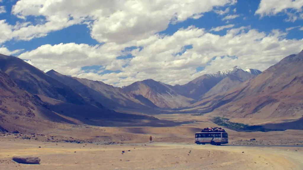 A remote road winding through a mountain valley, suggesting the beginning of a journey.